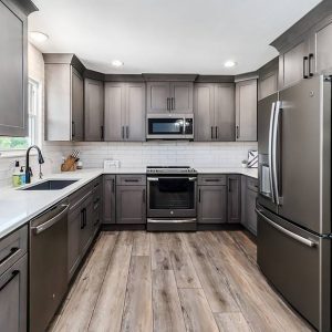 A kitchen with grey cabinets and wood floors