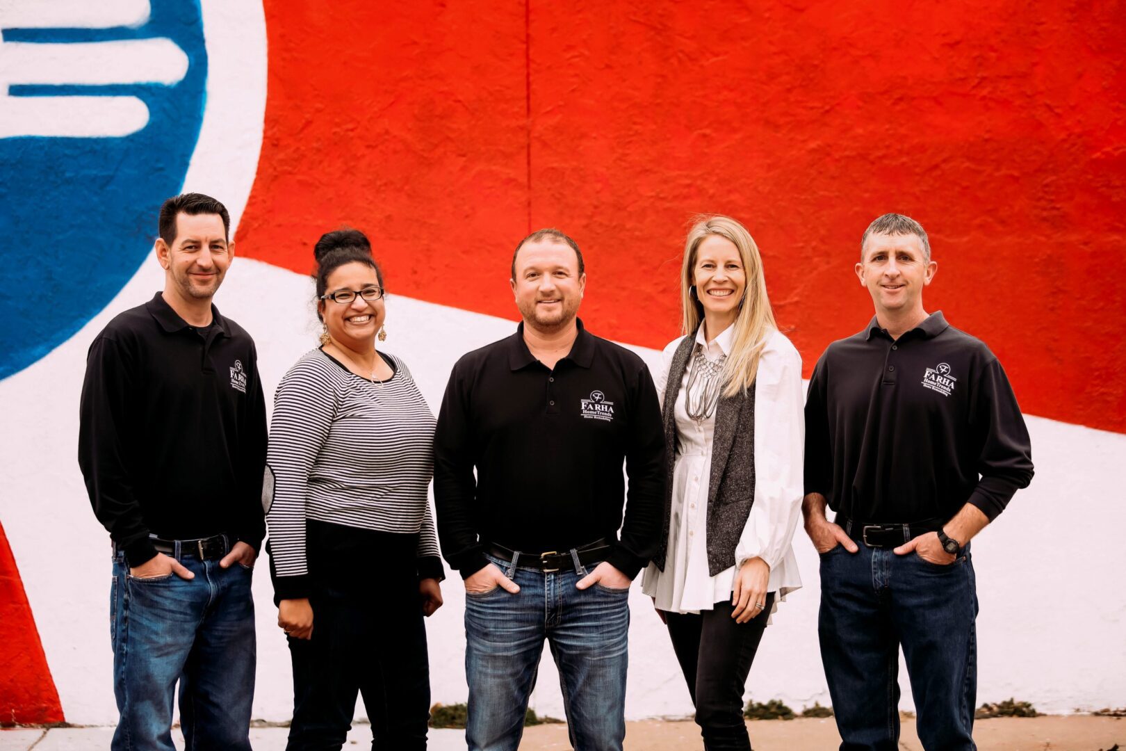 A group of people standing in front of a wall.