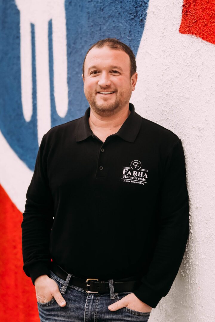 A man standing in front of a wall with a logo on it.