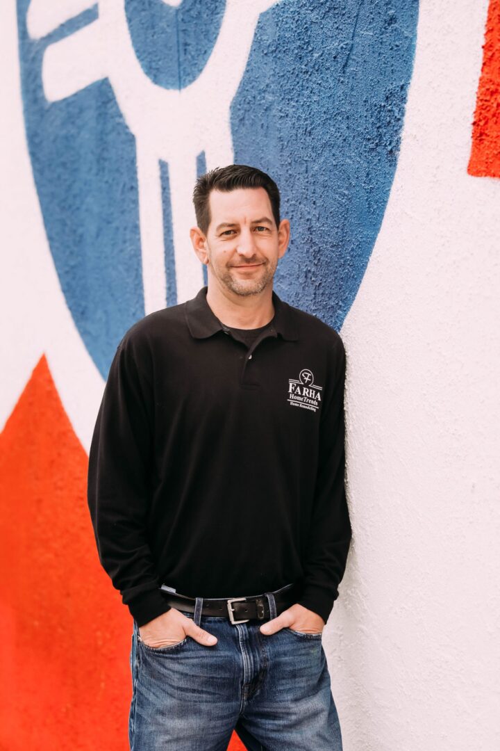 A man standing in front of a wall with some type of painting on it.