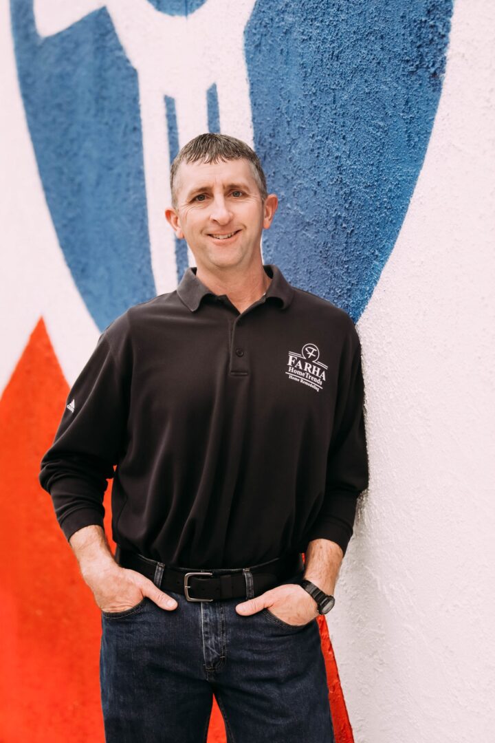 A man standing in front of a wall with his hands in his pockets.